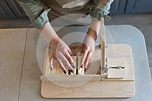 A woman makes handmade natural soap.The finished soap is cut into pieces using special machine. Home spa. Small business