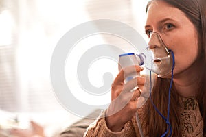 Woman makes inhalation nebulizer at home. holding a mask nebulizer inhaling fumes spray the medication into your lungs sick