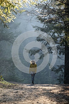 Woman makes a light jog through the misty forest in the morning, dawn and foggy morning in the woods.