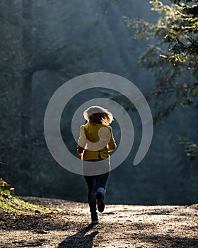 Woman makes a light jog through the misty forest in the morning, dawn and foggy morning in the woods.