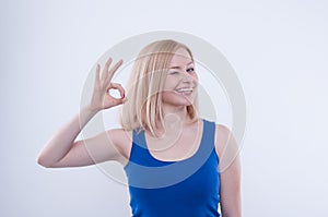 Woman makes ok, good sign with her hand and beaming.