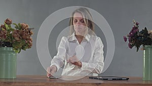 Woman makes an order online by phone at a table on a grey background