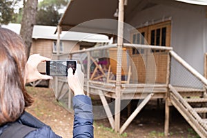 Woman makes a picture of her wooden rental cottage with phone