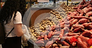 Woman makes purchases in the supermarket, healthy food, potatoes puts in a basket to be weighed on a scale in the market