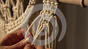 A woman makes a rope craft in a creative workshop. Woman's hands tie knots on macrame threads and create a creative