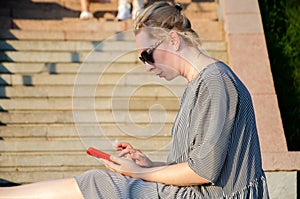 Woman makes shopping on Internet or communicates in instant messengers from smartphone while in park