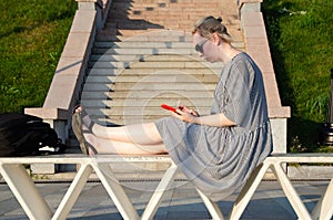 Woman makes shopping on Internet or communicates in instant messengers from smartphone while in park