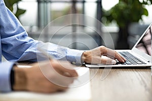 Woman makes some notes in notebook from laptop.