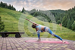 Woman makes Utthita Parshvakonasana in the mountains