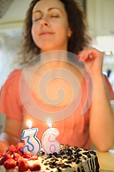 Woman makes a wish before blowing candle in shape