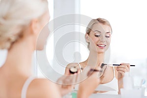 Woman with makeup brush and eyeshade at bathroom