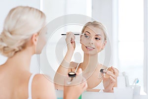 Woman with makeup brush and eyeshade at bathroom
