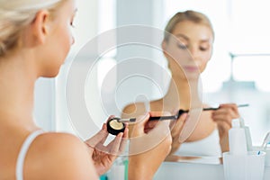 Woman with makeup brush and eyeshade at bathroom