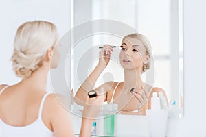 Woman with makeup brush and eyeshade at bathroom