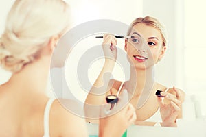 Woman with makeup brush and eyeshade at bathroom