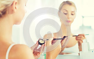 Woman with makeup brush and eyeshade at bathroom