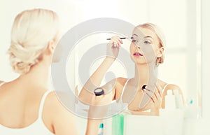 Woman with makeup brush and eyeshade at bathroom