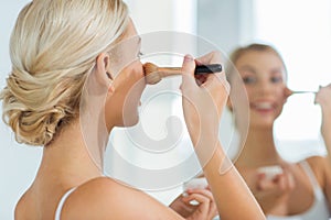 Woman with makeup brush and powder at bathroom