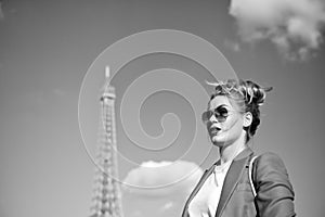 Woman with makeup and sunglasses in front of blue sky and top of Eiffel Tower on background. Stylish Parisian concept