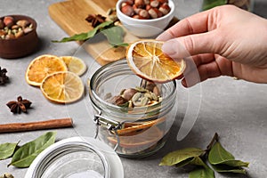 Woman making aromatic potpourri at grey table, closeup