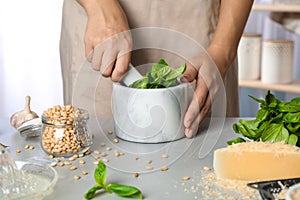 Woman making basil pesto sauce at kitchen