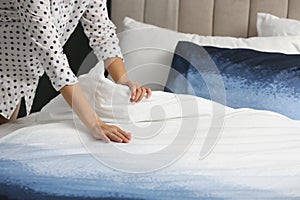 Woman making bed at home, closeup of hands