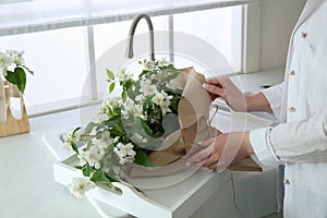 Woman making bouquet with jasmine flowers in kitchen, closeup