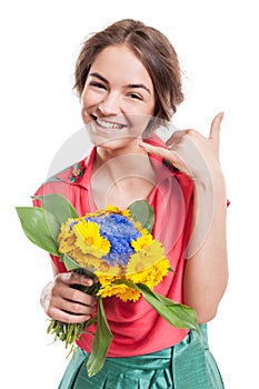 Woman making call me gesture with hand while holding flowers