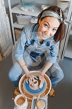 Woman making ceramic dishware on pottery wheel with clay, workshop and leisure concept