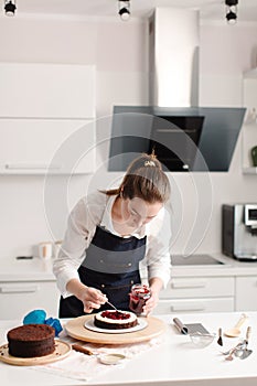Woman making chocolate cake in kitchen, close-up. Lays berries. Cake making process, Selective focus