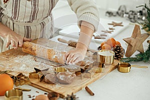 Woman making christmas gingerbread cookies in modern white kitchen close up. Hands kneading gingerbread dough with rolling pin,