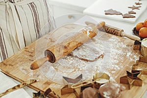 Woman making christmas gingerbread cookies in modern white kitchen close up. Hands kneading gingerbread dough with rolling pin,