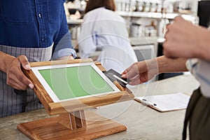 Woman making contactless card payment at cafe, close up