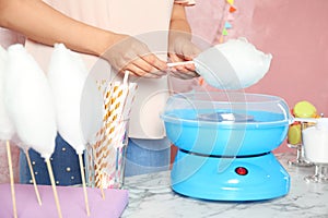 Woman making cotton candy using modern machine at table