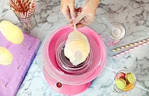 Woman making cotton candy using machine at table, top view