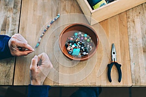 Woman making craft jewelry, with colored stones