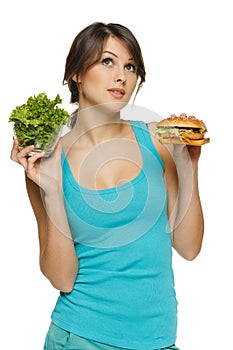 Woman making decision between healthy salad and fast food