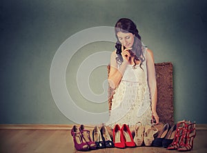 Woman making decisions picking right pair of high heel shoes