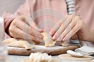 Woman making dumplings (varenyky) with cottage cheese at table, closeup