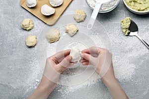 Woman making dumplings (varenyky) with potato at grey table, top view