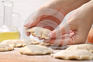 Woman making dumplings (varenyky) with tasty filling at table, closeup