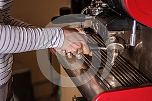 Woman making espresso coffee on a professional machine in the bar