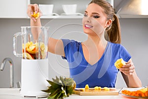 Woman making fruits smoothies with juicer machine