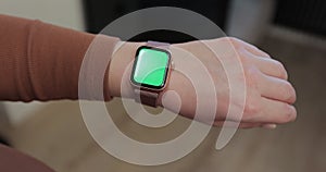 Woman making gestures on a wearable smartwatch computer device, close up. Smart watch with a green screen chroma key.