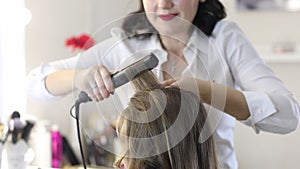 Woman making hairdressing for teen pretty girl with long hair.