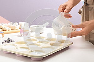 Woman making hand made soap bar with lavender flowers at table