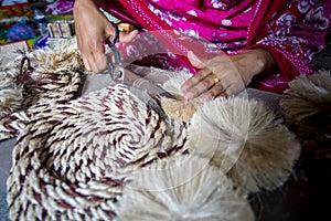 A woman making handicrafts is smoothing the fibers