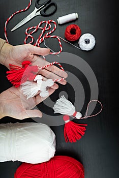 Woman making handmade traditional martisor, from red and white strings with tassel. Symbol of holiday 1 March, Martenitsa, Baba photo