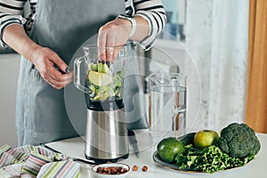 Woman making healthy green smoothie. Vegetarian, clean eating lifestyle concept