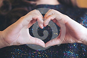 A woman making heart hand sign though her shirt